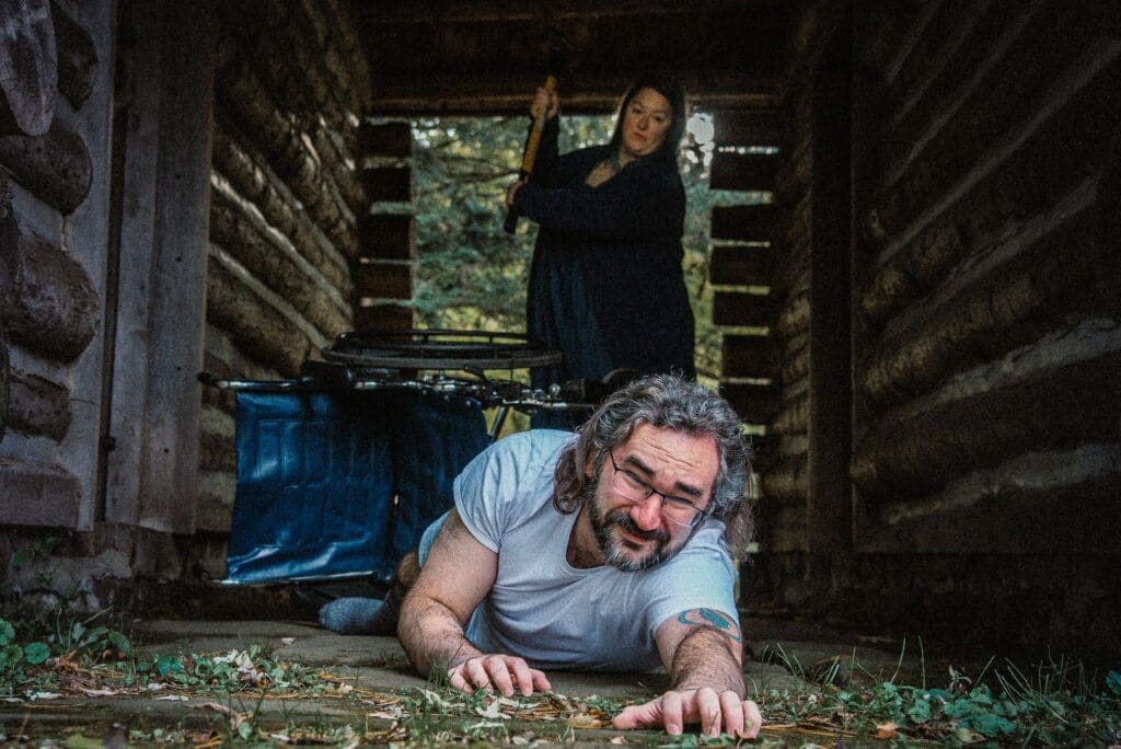 A man and woman in the woods with an ax.