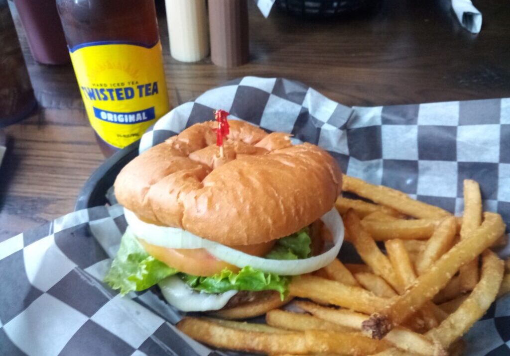 A sandwich and fries on a checkered plate.