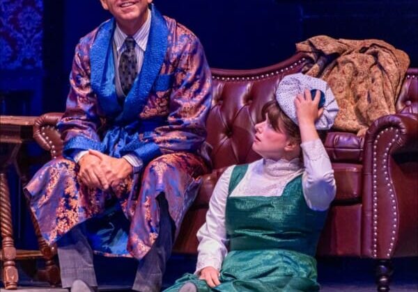 Man and child in period costumes on stage.