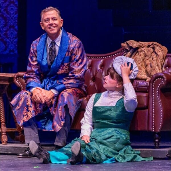 Man and child in period costumes on stage.