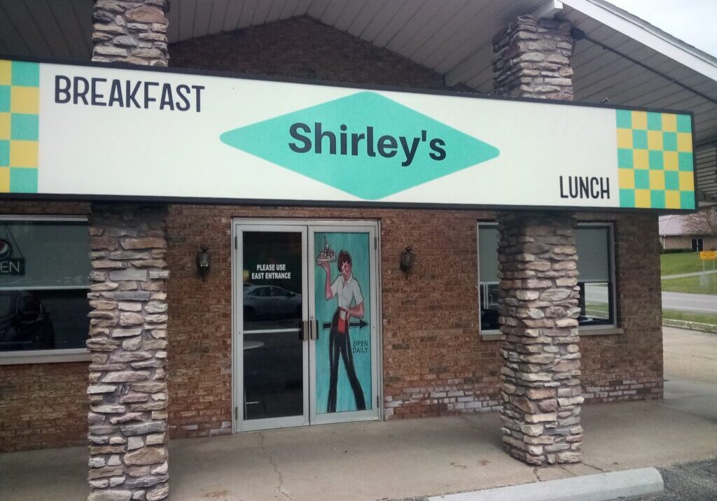 A woman standing in front of a restaurant entrance.