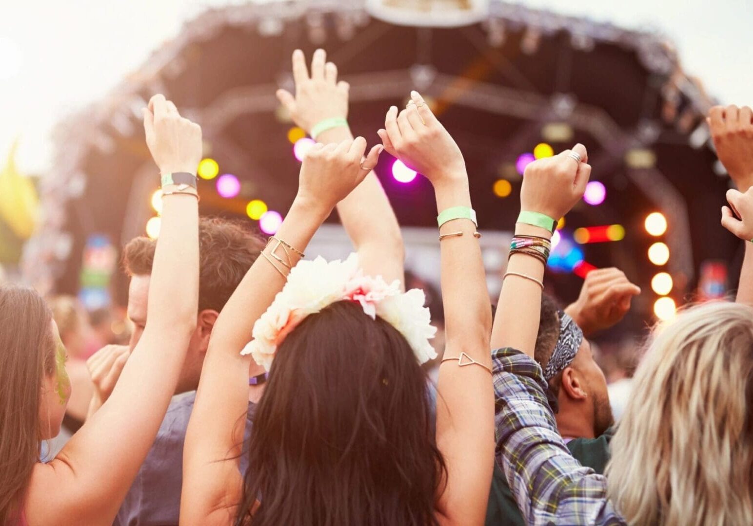 A group of people at an outdoor concert raising their hands.
